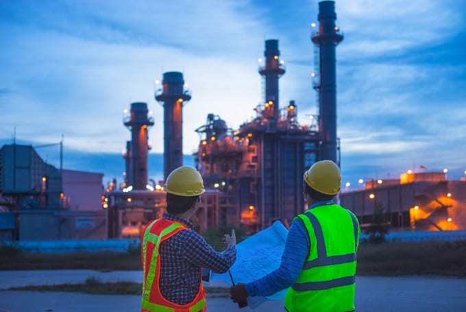 Stock image of 2 site workers at a power plant representing Lacima's software that provides a solution from structuring and trading, to risk management of oil and product portfolios. Crude and refined oil valuation and risk analysis